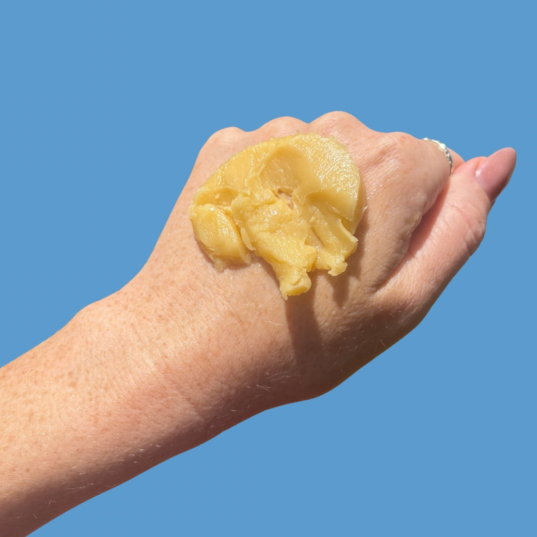 Hand with pile of Tallow balm on blue background