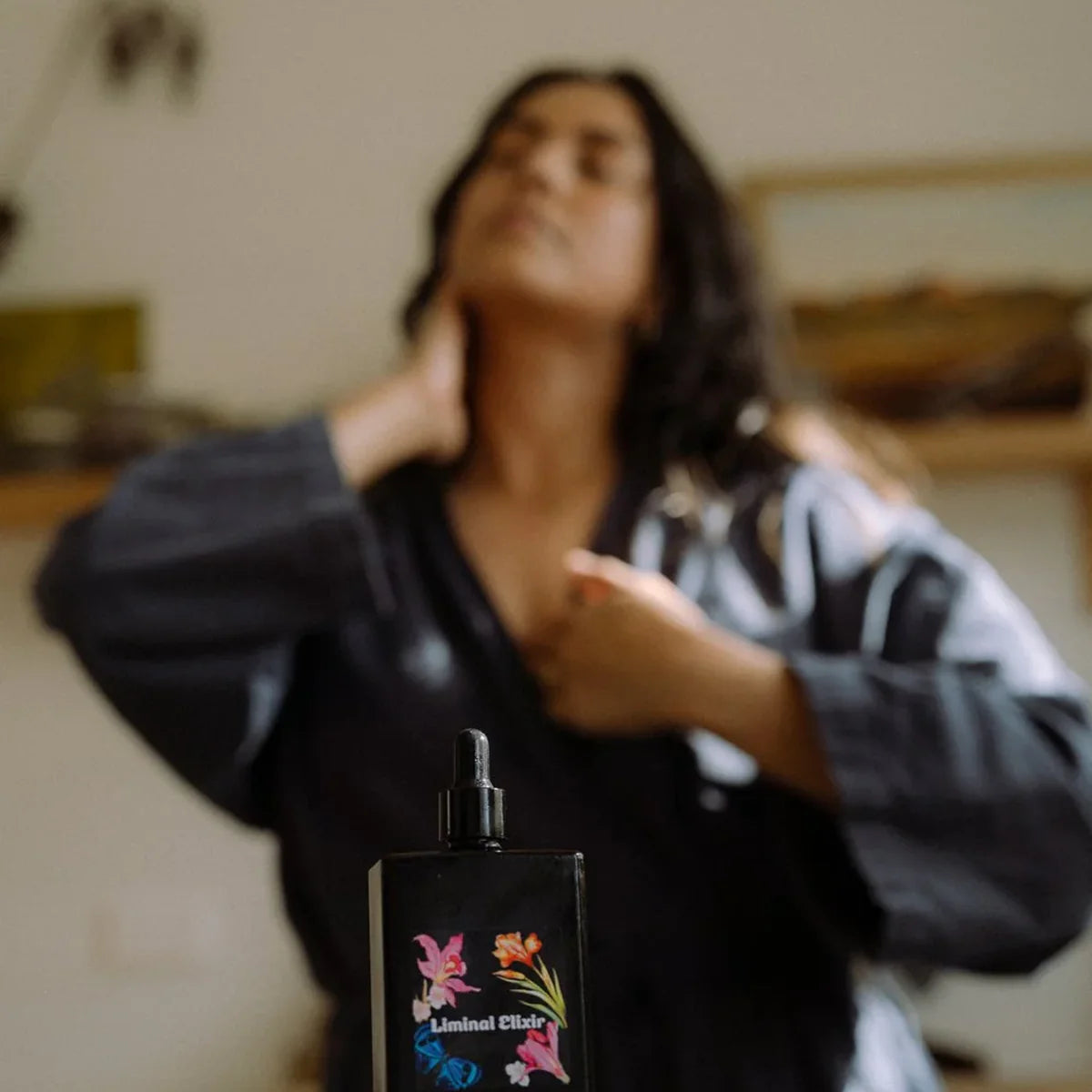 Bottle of oil with blurred woman massaging neck in background