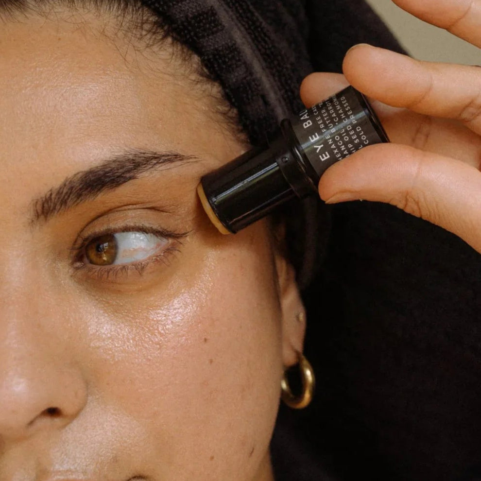 Person applying skincare with a balm stick near their eye