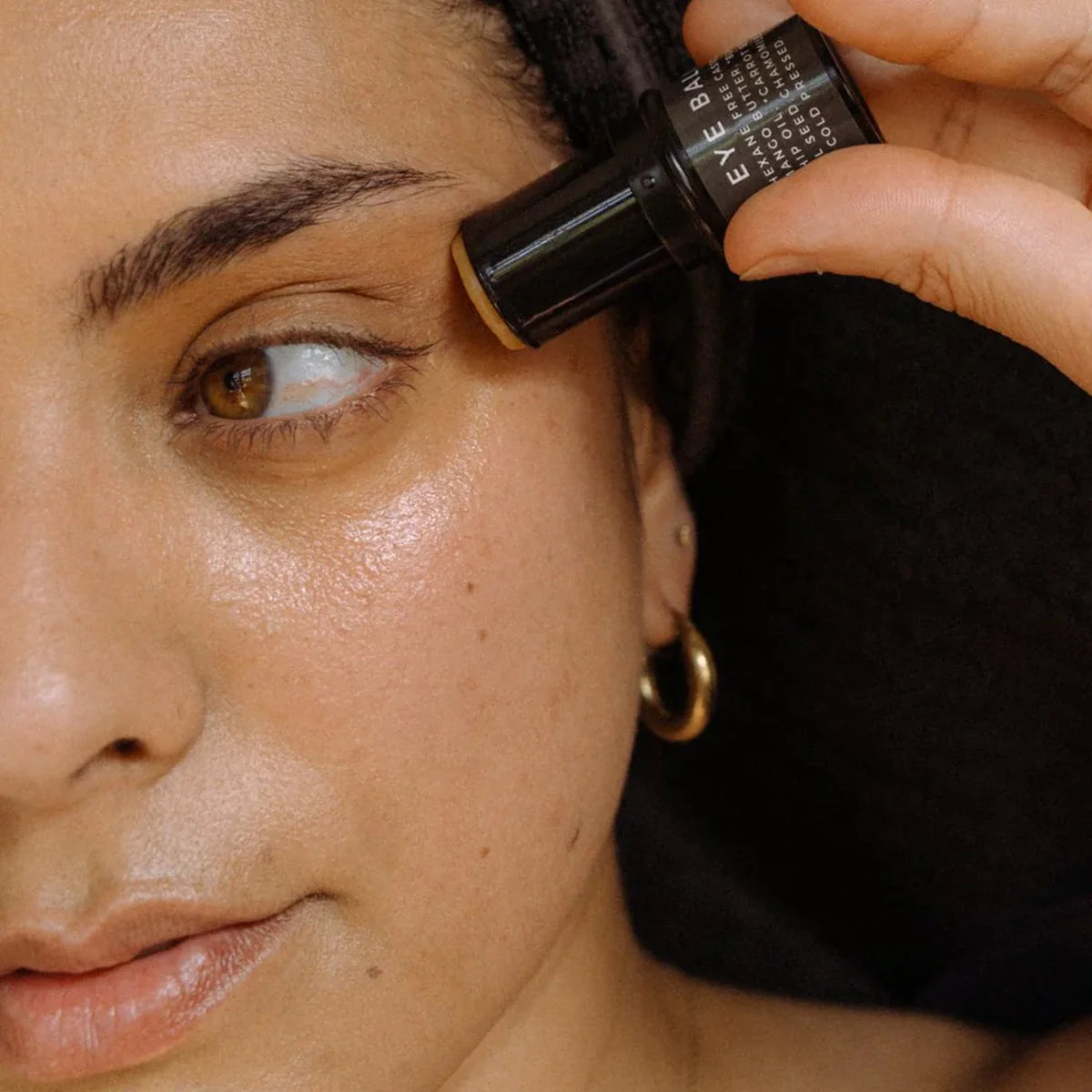 Woman applying eye balm to side of eye area