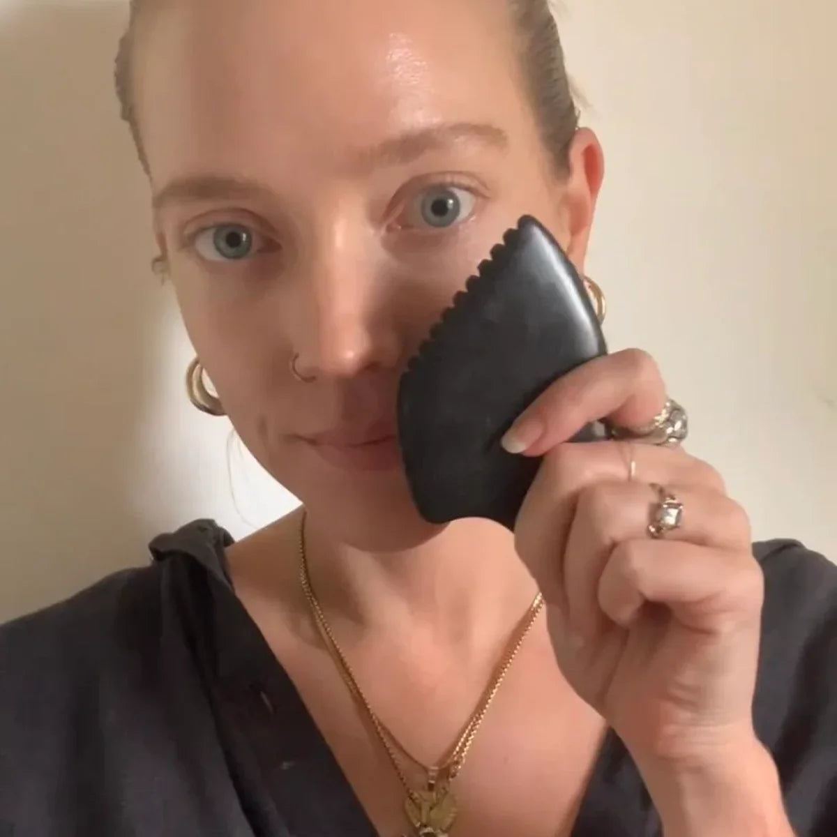 Woman holding Bian Stone Gua Sha up to her face