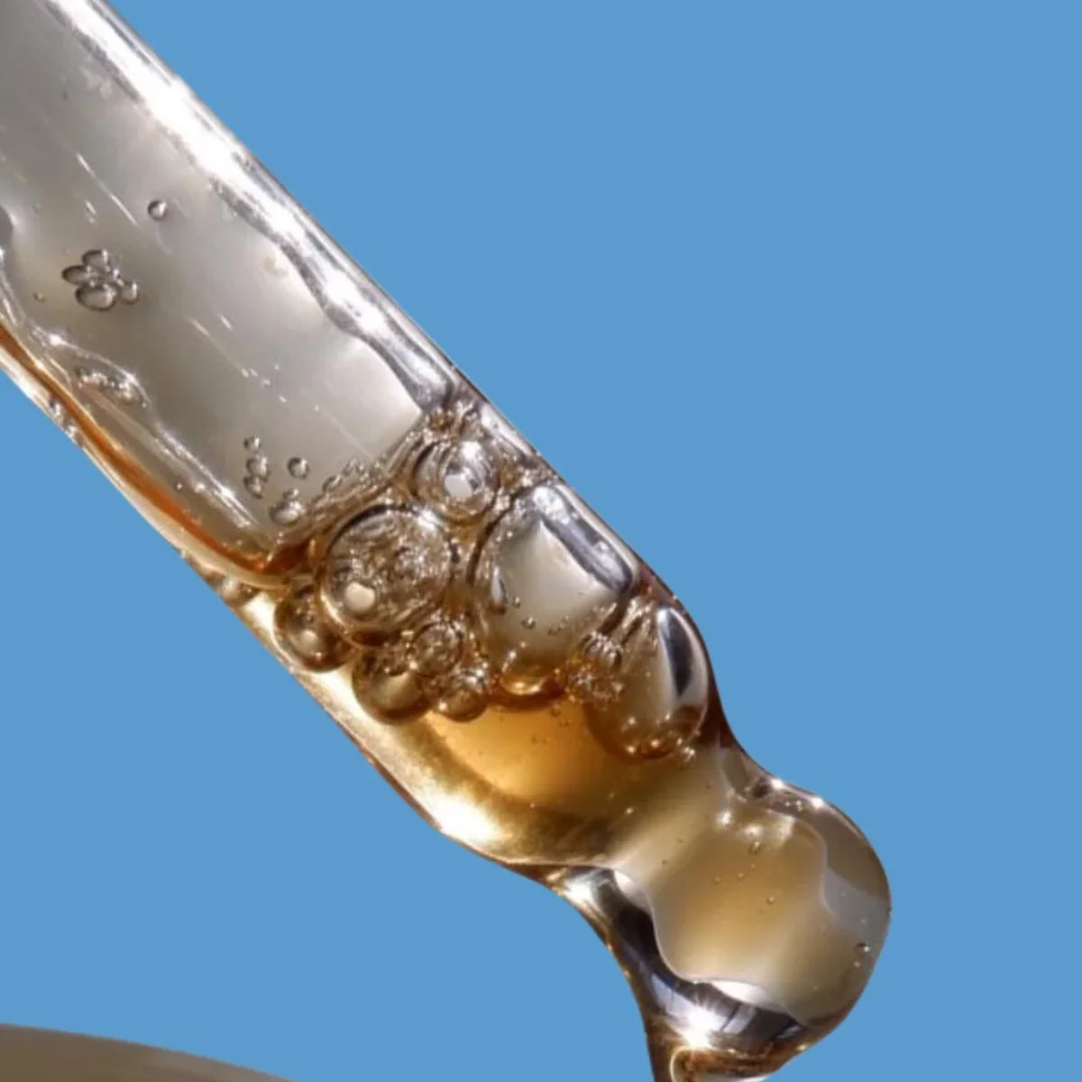 Close-up of a dropper with liquid against a blue background