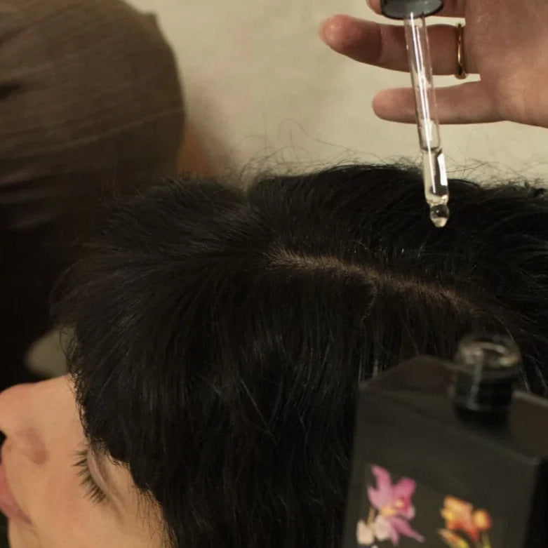 Dropper adding scalp oil to scalp of girl