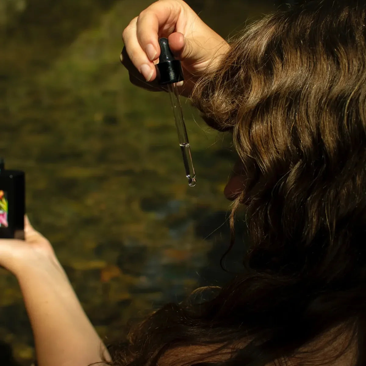Dropper applying hair oil to hair.