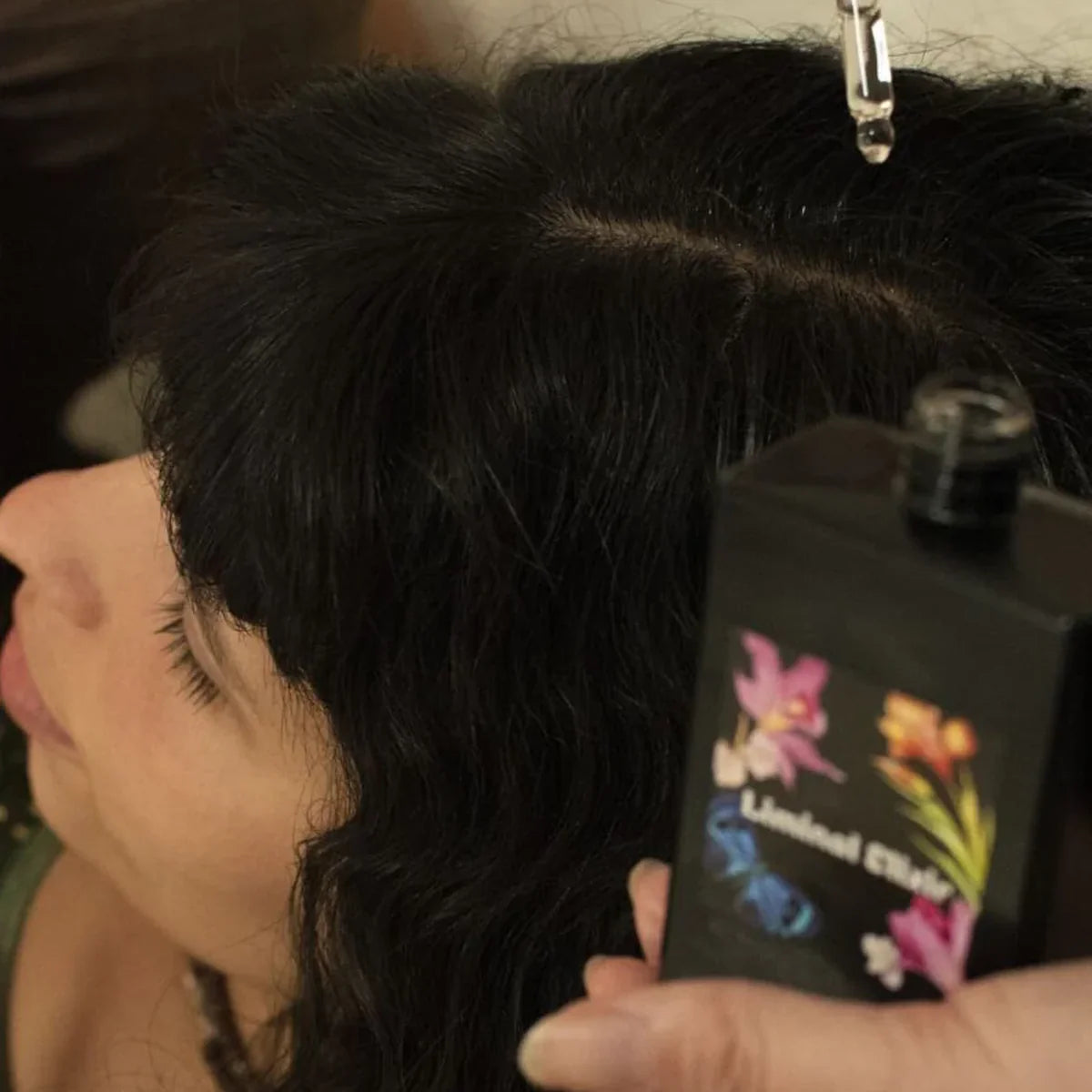 Woman dropping hair oil onto scalp