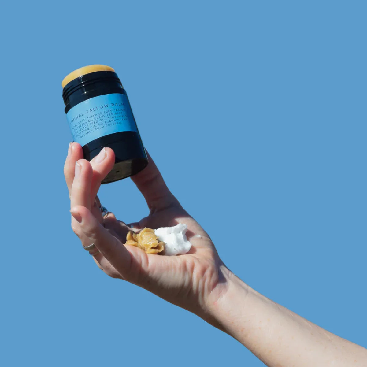 Hand holding tallow balm stick with castor oil and tallow in hand