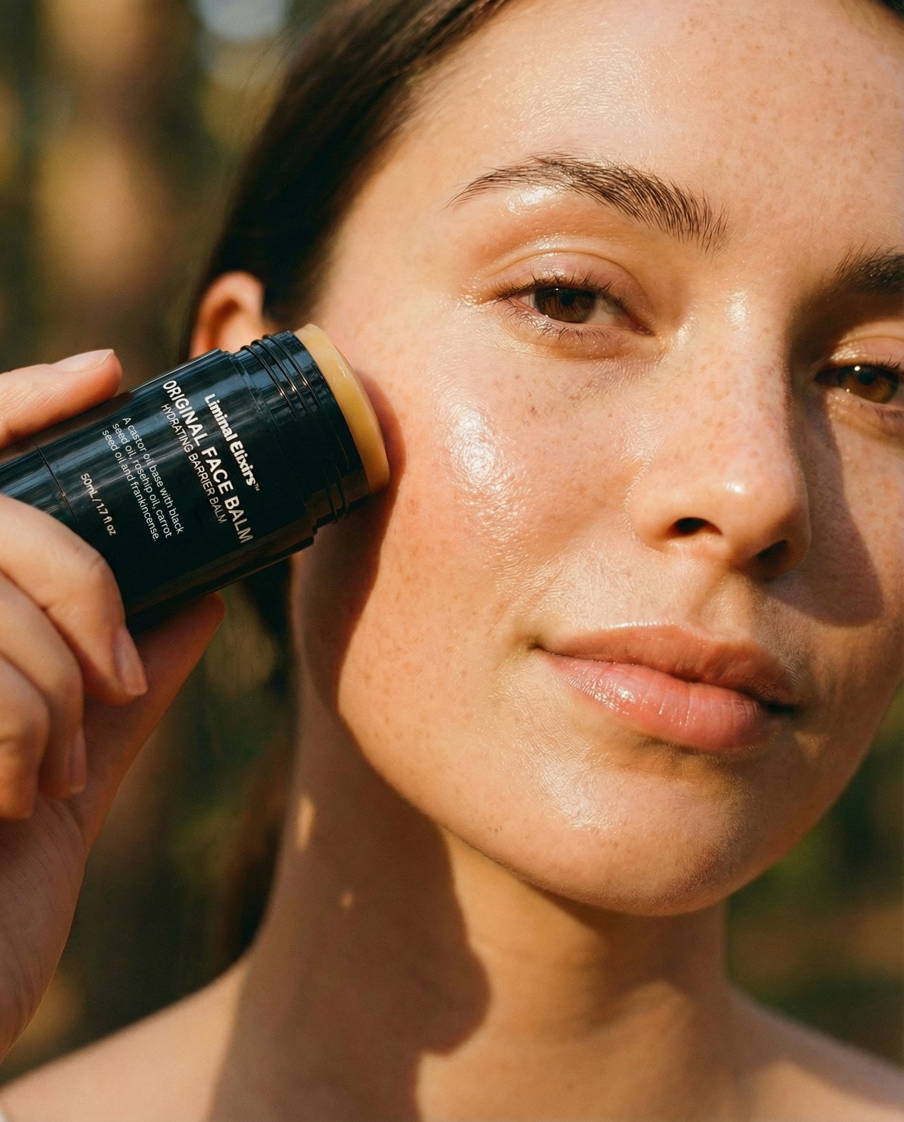 Person applying Liminal face balm to their face outdoors