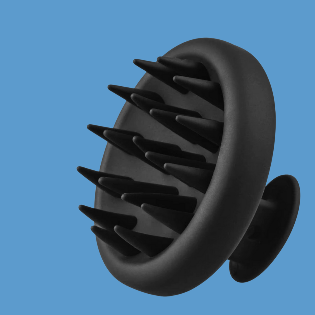Side on photo of a silicone scalp massager on a blue background