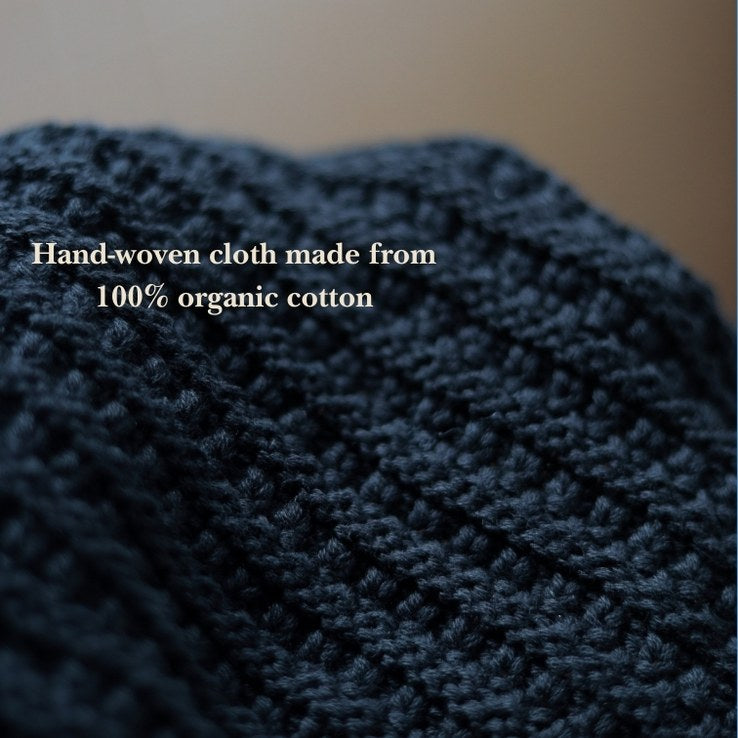 Hand-woven cloth made from 100% organic cotton with a blurred background.