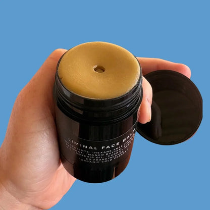 Hand holding face balm with lid off