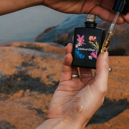 Hand holding bottle of oil and other hand dropping oil on hand