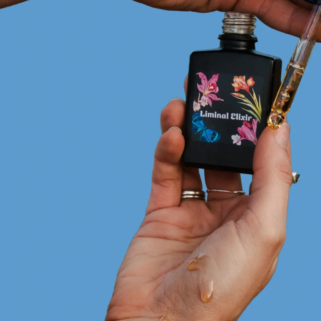 Hand holding a small black bottle labeled &