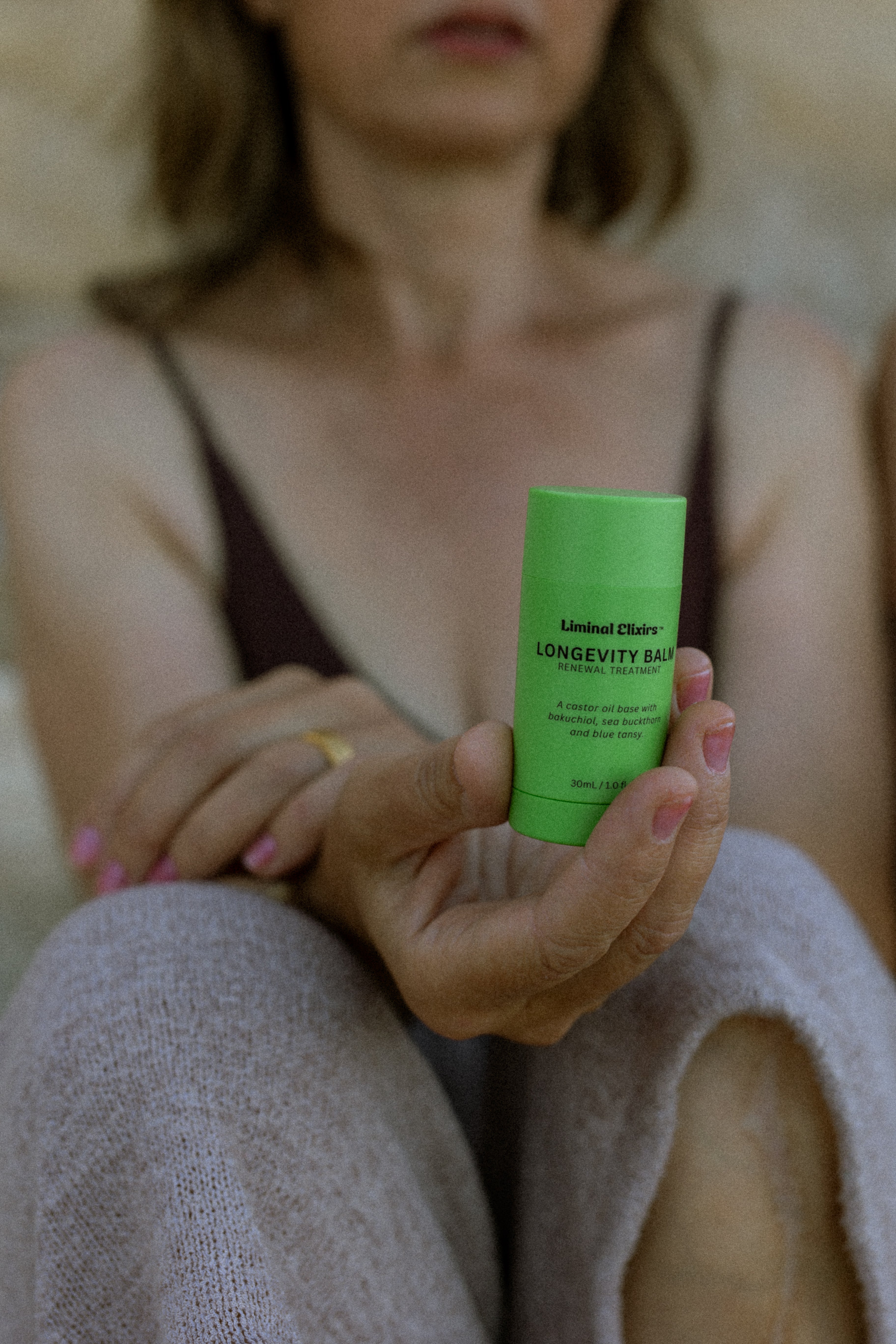 woman holding a Liminal Longevity Balm while seated comfortably
