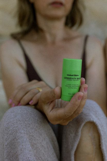 woman holding a Liminal Longevity Balm while seated comfortably